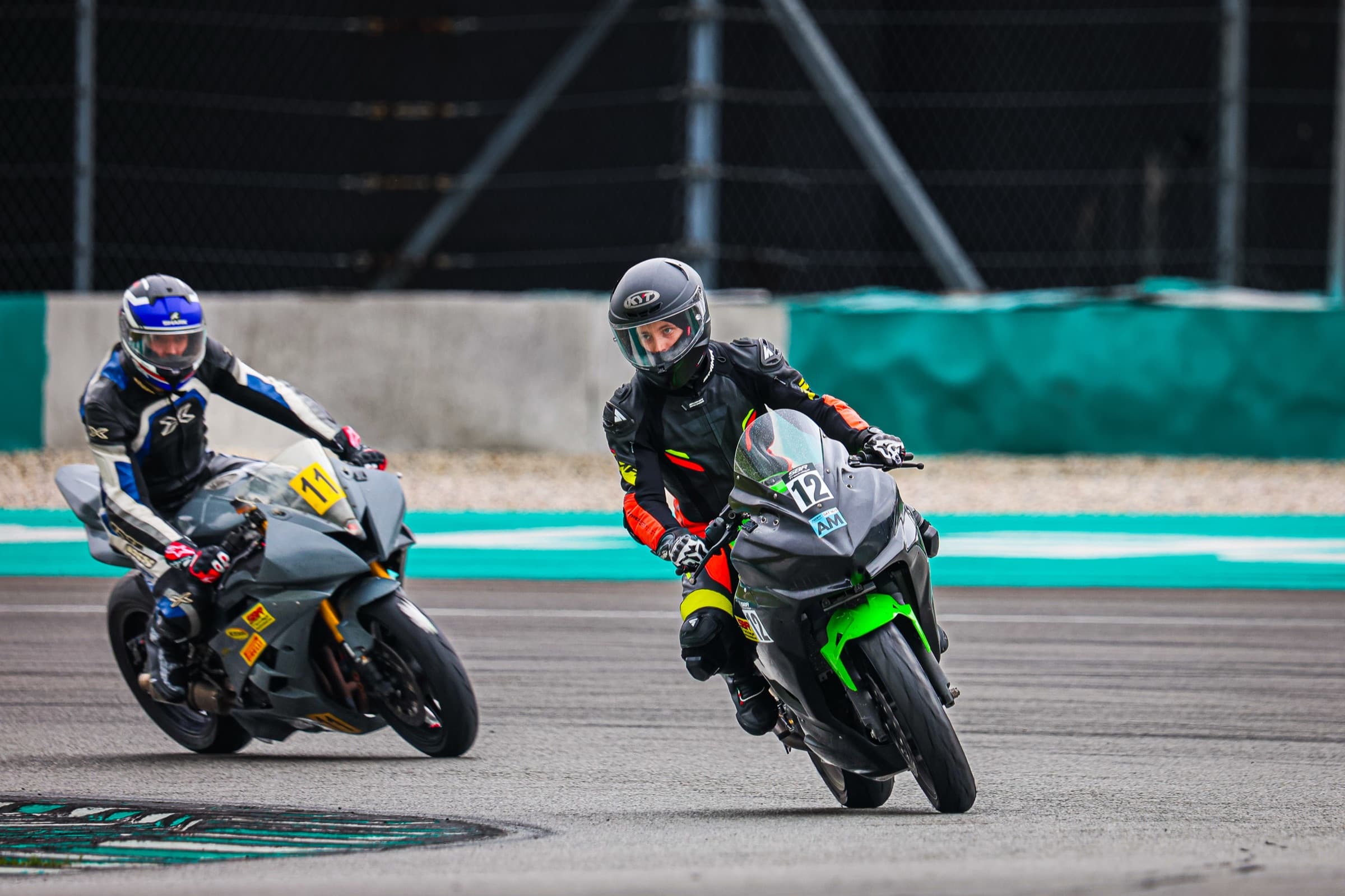 Two riders leaning hard through a Sepang corner